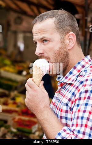 Stattlicher Mann mit Bart ein Eis essen, Deutschland Stockfoto