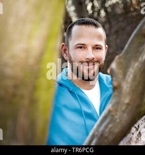 Schöner Mann in der Natur an einem Baumstamm, Deutschland Stockfoto