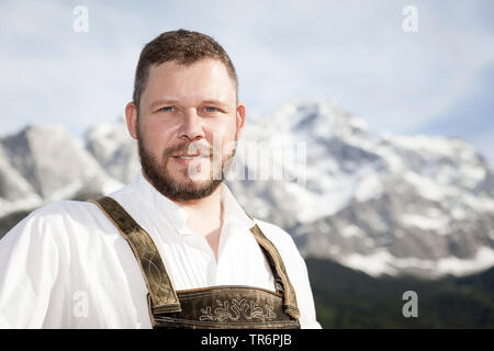 Schönes, gut aussehenden Mann im Bayerischen traditionelle Kleidung vor der Zugspitze, Deutschland, Bayern Stockfoto