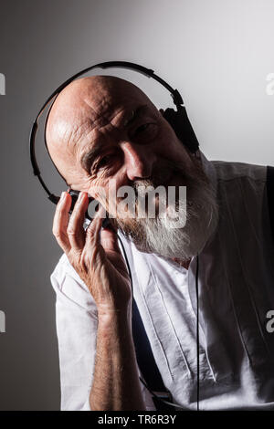 Ältere Glatze mann Hören von Musik über Kopfhörer, Deutschland Stockfoto