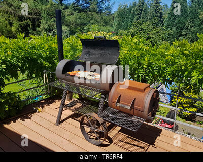 Grill Fleisch in einem Barbecue-Smoker auf einer Terrasse, Deutschland Stockfoto