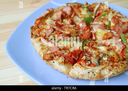 Teller köstliche Schinken und Wurst Pizza serviert auf hölzernen Tisch Stockfoto
