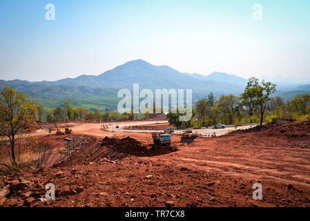 Road Construction Equipment und Road Repair Maschine Graben an der Baustelle mit schweren Tieflöffel Motor Arbeiter am Hang von steilen Berg ba Stockfoto