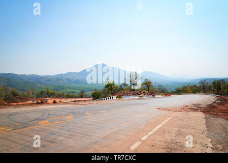 Road Construction Equipment und Road Repair Maschine Graben an der Baustelle mit schweren Tieflöffel Motor Arbeiter am Hang von steilen Berg ba Stockfoto