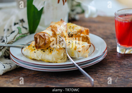 Ein Glas türkischen Sorbet und Scheiben der frisch gebackene Hausgemachte borek Gebäck auf den Tisch, schließen. Stockfoto