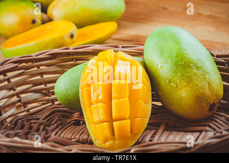 In der Nähe von frischem Grün Dashehari Mangos und seine Schicht in Holz- korb auf hölzernen Tisch platziert. Stockfoto