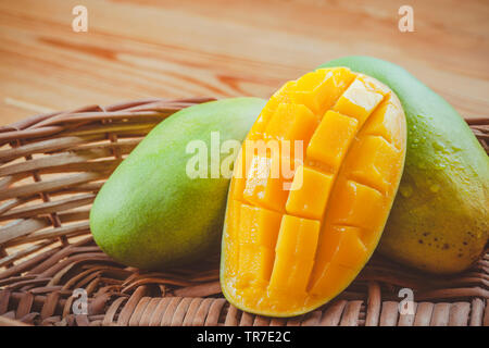In der Nähe von frischem Grün Dashehari Mangos und seine Schicht in Holz- korb auf hölzernen Tisch platziert. Stockfoto