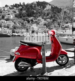 Schwarzweiß-Bild der Hafen von Symi in Griechenland mit einem roten Roller im Vordergrund. Stockfoto