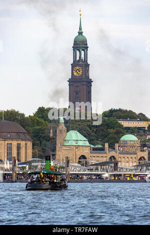 Historisches Dampfschiff vor ST. Pauli Piers in Hamburg mit berühmter Michaelskirche im Hintergrund Stockfoto