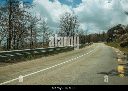 Straße durch einen verbrannten Waldes über einen felsigen Landschaft der Serra da Estrela. Das höchste Gebirge auf dem portugiesischen Festland. Stockfoto