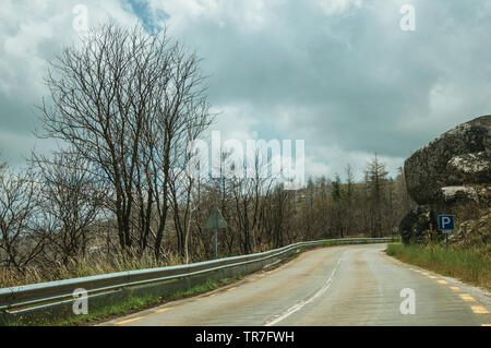 Straße durch einen verbrannten Waldes über einen felsigen Landschaft der Serra da Estrela. Das höchste Gebirge auf dem portugiesischen Festland. Stockfoto