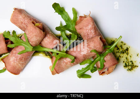 Gekochte Zunge mit Füllung und Sauce auf einem weißen Teller. Stockfoto