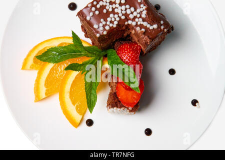 Schokoladenkuchen mit Orangen und Erdbeeren auf einem weißen Teller. Stockfoto