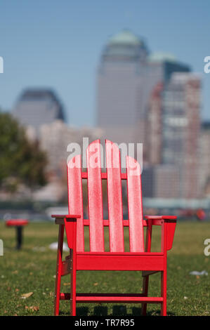 Rote hölzerne Rasen Stuhl gegen Lower Manhattan Kulisse. Stockfoto