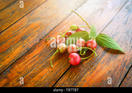 Die jamaikanische kirsche frucht und Blatt auf hölzernen Hintergrund/lokalen Obst in Asien andere Namen malaiische Cherry Calabura jam Baum Stockfoto