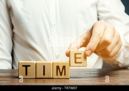 Ein Mann legt Holzblöcke mit dem Wort Zeit. Konzept der Zeit Verwaltung und ordnungsgemäße Verteilung. Planung Wirtschaft und Arbeit. Business Jugend. Analyse Stockfoto