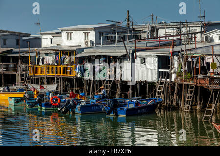 Ein Fischer Mends Netze außerhalb Bunte Häuser auf Stelzen, das Fischerdorf Tai O, Hongkong, China Stockfoto
