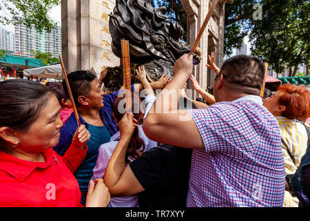 Chinesische Touristen reiben Sie den Drachen Statue für gutes Glück am Eingang zu Wong Tai Sin Tempel, Hongkong, China Stockfoto