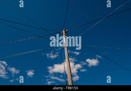 Alten hölzernen Strommast mit Stromleitungen gehen in verschiedene Richtungen. Stockfoto