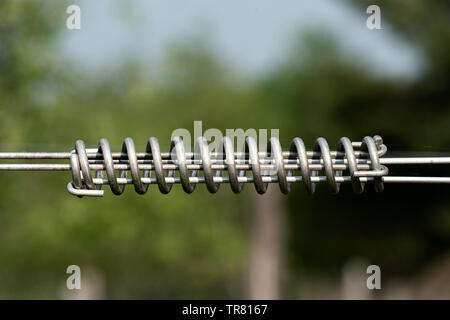 Spiralförmige kabel Spanner für elektrischen Zaun außen mit bokeh Hintergrund Stockfoto