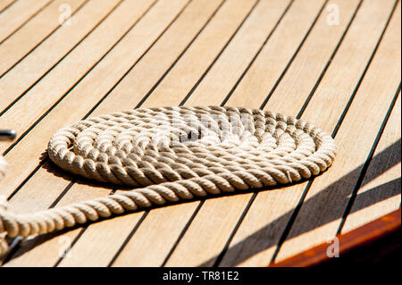 Seil ordentlich aufgerollt auf der Holzterrasse eines Bootes. Stockfoto