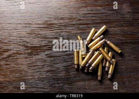 Leere Patronenhülsen auf einem dunklen, hölzernen Tisch. Stockfoto