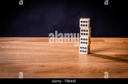 Ein Stapel von Würfel auf einem holztisch vor einem schwarzen Hintergrund. Stockfoto