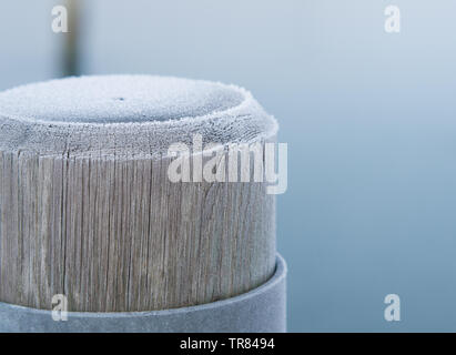 Holz- Liegeplatz Pole auf einem Einfrieren. Stockfoto