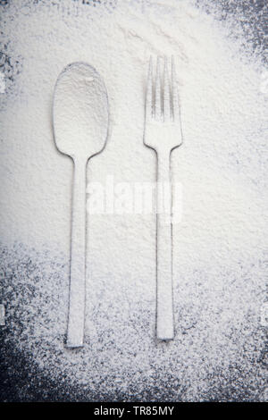 Löffel und Gabel Silhouette mit Mehl auf dunklem Hintergrund Textur Stockfoto