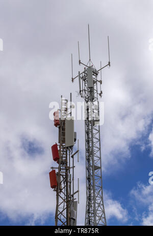 Comunication Türmen, mit Panels und Antennen, mit weißen Wolken Hintergrund Stockfoto