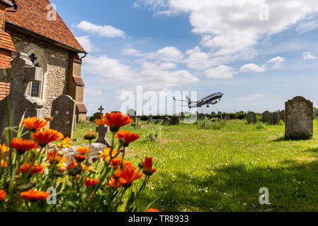 Airliner Flugzeug vom Flughafen London Southend, Southend On Sea, Essex, Großbritannien, St Laurence & Allerheiligen Kirche, Blumen und Grabsteine. Stockfoto