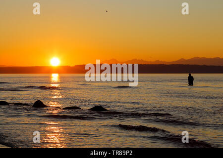 Ein Fischer ist Angeln Golden Gardens Park, Seattle, Washington bei einem herrlichen Sonnenuntergang Stockfoto