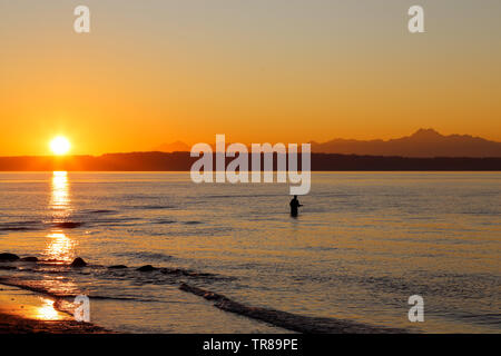 Ein Fischer ist Angeln Golden Gardens Park, Seattle, Washington bei einem herrlichen Sonnenuntergang Stockfoto