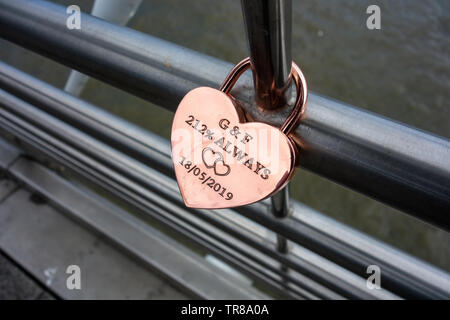 Golden personalisiertes Liebesschloss, befestigt an der Hungerford Bridge, London, mit G&F 212% immer 18/05/2019 eingeschrieben auf dem Schloss und zwei Liebesherzen Stockfoto