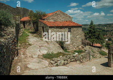 Gotisches Haus aus Stein in Gasse am Hang über felsiges Gelände und Wand bei Sortelha. Eine erstaunliche und gut erhaltene mittelalterliche Weiler in Portugal. Stockfoto