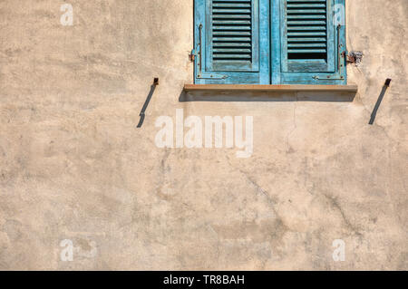 Foto eines einsamen verwitterten, grünen Fensterläden gegen eine Blasse gelb plater Wand. In den Cinque Terre Italien. Stockfoto