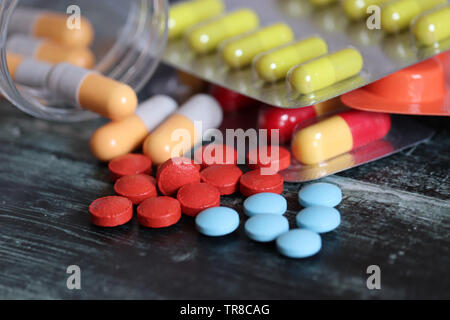 Pillen und Kapseln auf dunklen Holztisch, viele bunte Medikation close-up. Konzept der Apotheke, Vitamine, Gesundheit Stockfoto