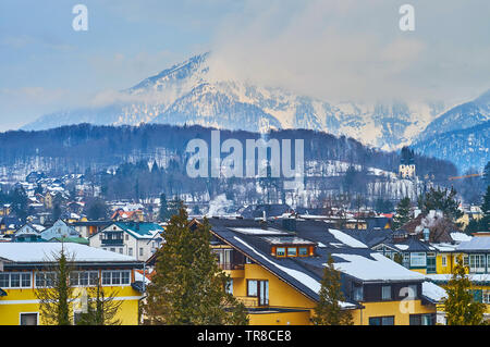 Genießen Sie den Blick über die Dächer von farbenfrohen Cottages von Bad Ischl und der malerischen Alpenlandschaft, teilweise in weißen Wolken versteckt, Bad Ischl, Salzkammerg Stockfoto