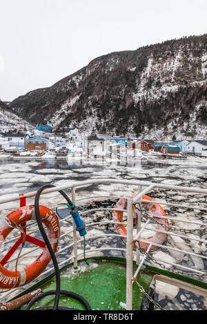 Waterfront mit schwebenden Pfannkucheneis am Ausgang von Grey River, die zusammen ein Fjord gekuschelt wird, gesehen von der Fähre Marine Voyager, Neufundland Stockfoto