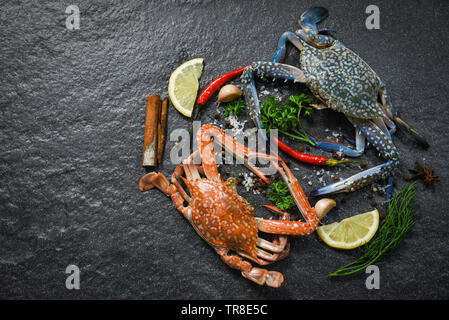 Frische rohe Krabben gekochten Muscheln Meeresfrüchte und gedämpfte Krabben mit Kräuter und Gewürze chili Zitrone, Knoblauch und Dill auf dunklem Hintergrund Stockfoto