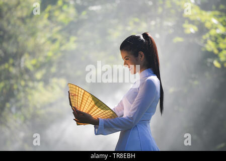 Asien Frau Vietnam oder chinesischen Stil Kleid / Portrait von schönen jungen Mädchen vietnamesischen traditionellen Kostüm mit Hut weben Blatt in der Hand auf n Stockfoto