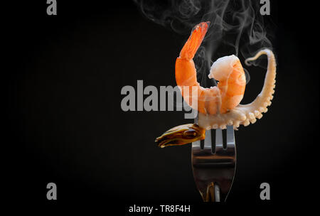 Garnele auf Gabel/gekochte Meeresfrüchte Garnelen mussel squid Octopus Tentakeln der Ozean Gourmet Dinner in der Gabel auf schwarzen dunklen Hintergrund Stockfoto