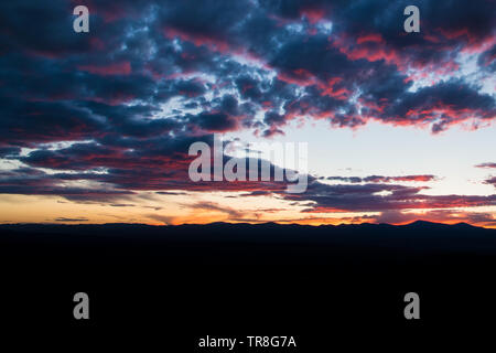 Lila und rosa umreißt schöne Wolken bei Sonnenuntergang über einem Berg Silhouette gegen den Himmel - Jemez Bergen in der Nähe von Santa Fe, New Mexico Stockfoto