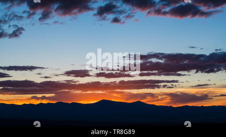 Sonnenuntergang Silhouetten einer Bergkette und beleuchtet ein dramatischer Abendhimmel mit lila und rosa Wolken - Jemez Bergen in der Nähe von Santa Fe, New Mexico Stockfoto