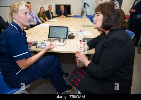 East Kilbride, UK. 30. Mai 2019. EMBARGO BIS ZUM 31. Mai um 00:01 Bild: (links-rechts) Laura MacKinnon, Jeane Freeman. Neue Technologie, die es erlaubt, dass Patienten ihren Blutdruck zu Hause zu überwachen wird über Schottland gerollt werden. Die scale-up BP Initiative verringert die Notwendigkeit für GP Konsultationen, und kann helfen, genauere Messwerte zu liefern. Die Patienten werden gezeigt, wie sie ihre eigenen Blutdruck und Text die Ergebnisse eine App namens Florenz, oder Flo zu messen. Colin Fisher/Alamy leben Nachrichten Stockfoto