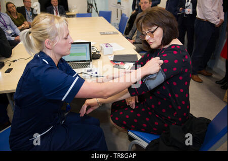 East Kilbride, UK. 30. Mai 2019. EMBARGO BIS ZUM 31. Mai um 00:01 Bild: (links-rechts) Laura MacKinnon, Jeane Freeman. Neue Technologie, die es erlaubt, dass Patienten ihren Blutdruck zu Hause zu überwachen wird über Schottland gerollt werden. Die scale-up BP Initiative verringert die Notwendigkeit für GP Konsultationen, und kann helfen, genauere Messwerte zu liefern. Die Patienten werden gezeigt, wie sie ihre eigenen Blutdruck und Text die Ergebnisse eine App namens Florenz, oder Flo zu messen. Colin Fisher/Alamy leben Nachrichten Stockfoto