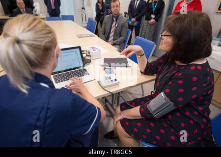 East Kilbride, UK. 30. Mai 2019. EMBARGO BIS ZUM 31. Mai um 00:01 Bild: (links-rechts) Laura MacKinnon, Jeane Freeman. Neue Technologie, die es erlaubt, dass Patienten ihren Blutdruck zu Hause zu überwachen wird über Schottland gerollt werden. Die scale-up BP Initiative verringert die Notwendigkeit für GP Konsultationen, und kann helfen, genauere Messwerte zu liefern. Die Patienten werden gezeigt, wie sie ihre eigenen Blutdruck und Text die Ergebnisse eine App namens Florenz, oder Flo zu messen. Colin Fisher/Alamy leben Nachrichten Stockfoto