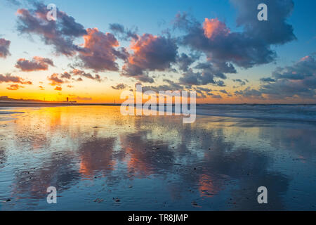 Sonnenuntergang an der Nordsee Strand von Oostende oder Oostende mit einem dramatischen cloud Reflexion und das urbane Stadtbild im Hintergrund, Westflandern, Belgien. Stockfoto