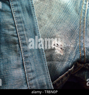 Ausgefranste Loch auf der Rückseite des alten blauen Jeans mit Doppelt genähte Nähte. Denim Jeans Hintergrund. Stockfoto