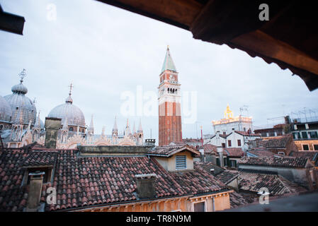 Basilika von St. Mark und der Glockenturm von St. Mark's Campanile (Campanile di San Marco) in Venedig, Italien. Sonnenuntergang. Aussicht vom Fenster. Stockfoto